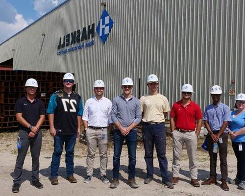 Group wearing 澳门足彩app hardhats gather outside 澳门足彩app钢 facility.